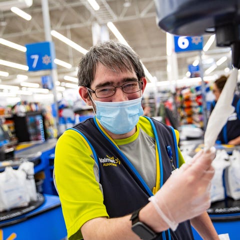 A Walmart employee wearing a mask and plastic glov