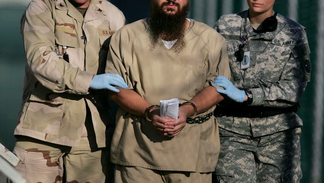 In this 2006 file photo, reviewed by a U.S. Department of Defense official, a shackled detainee is transported away from his annual Administrative Review Board hearing with U.S. officials, in Camp Delta detention center at the Guantanamo Bay U.S. Naval Base in Cuba.