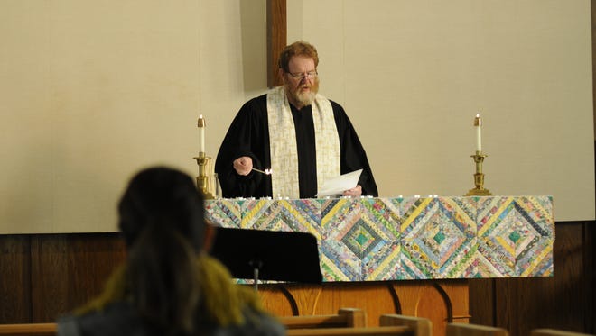 The Rev. John Fiscus lights candles as he reads the names of the 15 transgender people that were killed in the U.S. in 2016. The service at Peace United Church of Christ recognized Transgender Day of Remembrance.