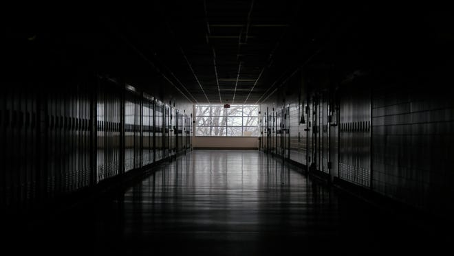 Dark school hallway with subtle daylight reflecting on lockers.