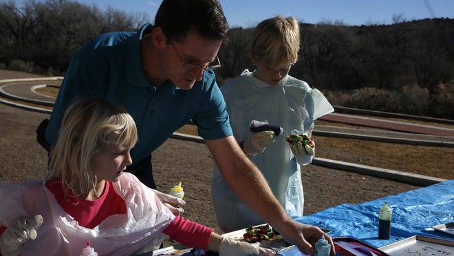 Museum Director Bart Wilsey helps his daughter, Emma, 5, and son, Cy, 11, tie dye clothing Saturday at the Farmington Museum at Gateway Park.