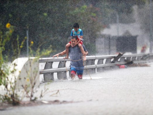 A man wades through floodwaters with a child on his