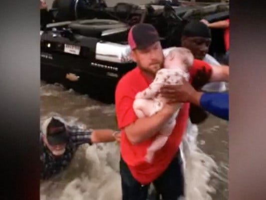 A Texas man holds a baby pulled from a vehicle on Saturday.