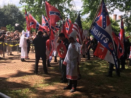 Members of the Ku Klux Klan rally in Charlottesville on Saturday as hundreds more gathered to oppose the event. The KKK is protesting the Charlottesville city council's decision this year to remove a statue of Confederate Gen. Robert E. Lee from a pu