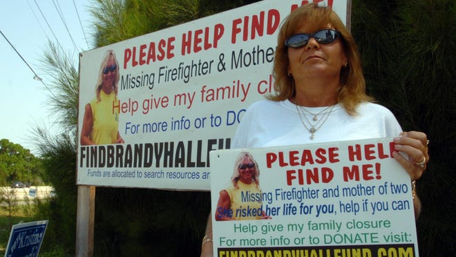 In a 2007 photo, Lynn Troup of West Melbourne poses at the intersection of Babcock Street and Malabar Road in Palm Bay near an advertisement for help finding her friend, Brandy Hall. This year marks the 10th anniversary of Hall’s disappearance in August 2006.