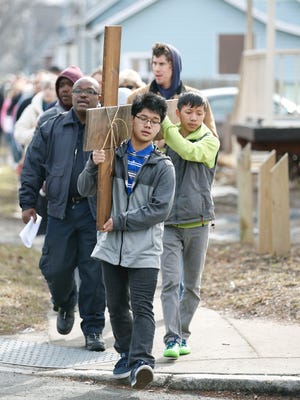 Rochester residents Ayewathy Myat, 16, and Kaw Moo, 15, carry the cross toward the fifth stop at an empty lot on Austin and Otis streets.