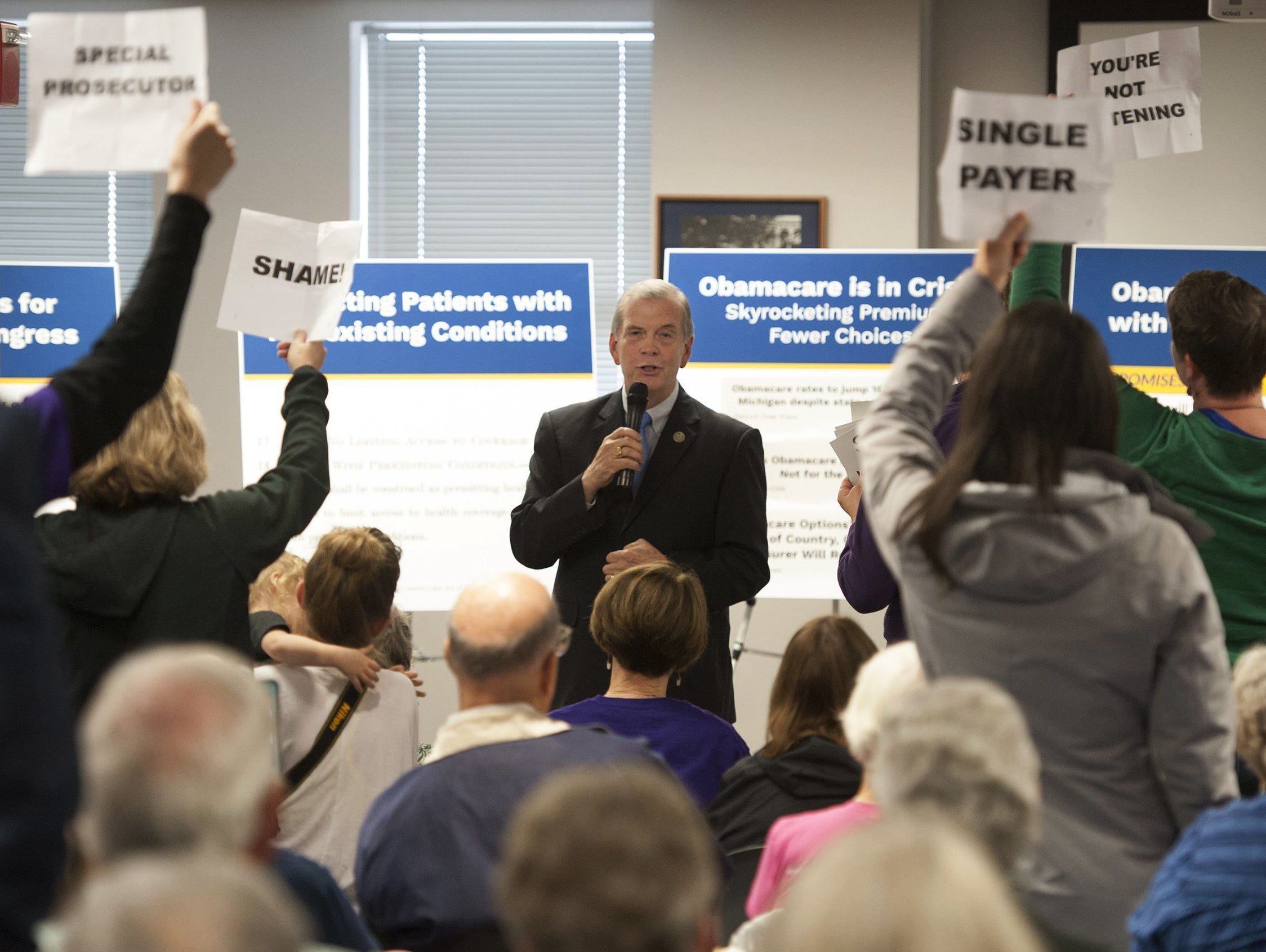 U.S. Rep. Tim Walberg, R-Mich., speaks as people stand in protest during a town hall meeting May 11, 2017, in Jackson, Mich.