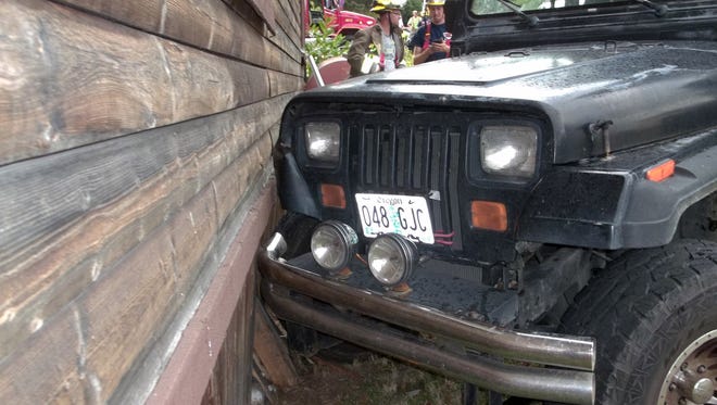 A Jeep allegedly driven by a 3-year-old before crashing sits against a house in Myrtle Creek, Ore.