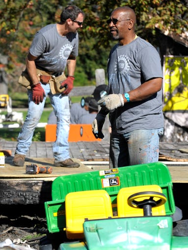 Creator Tyree Guyton, right, helps with the project.