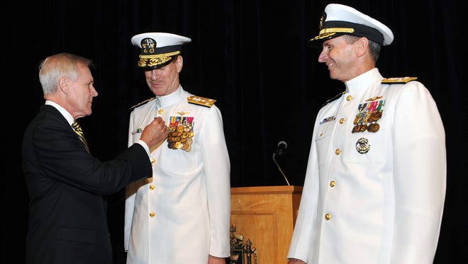 Vice Adm. Mike Miller, center, receives an award from Navy Secretary Ray Mabus during Miller's end-of-tour and retirement ceremony in July 2014. Miller, however, has not been allowed to retire pending the results of an investigation. Adm. Jon Greenert, chief of naval operations, is at right.