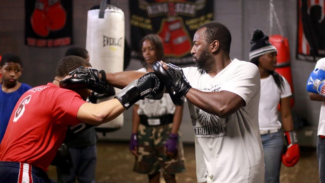Coach Carlo "Khali" Sweeney trains with a student using focus mitts at the Downtown Youth Boxing Gym in Detroit on Dec. 16, 2014. DYBG's mission is to develop good citizenship in urban youth through a demanding boxing program, strong academic support and a connection to the community through voluntary service.