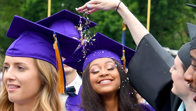 Graduates have glitter tossed on them in celebration by teachers as they walk between the members of the faculty during the recessional. Waynesboro High School beat the rain and held their commencement outside as planned on Saturday morning, May 19, 2018.