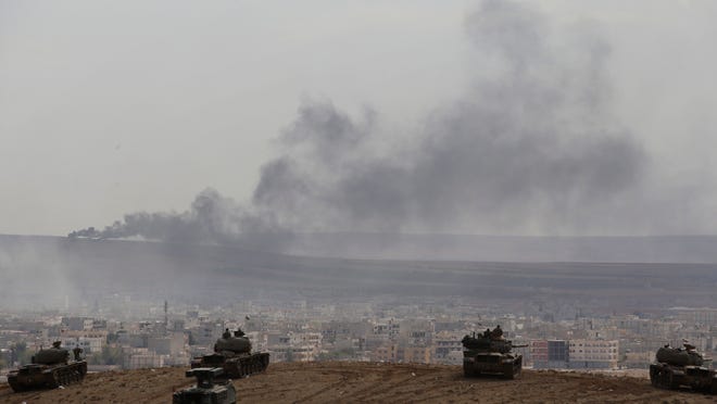 
Turkish soldiers in tanks and an armored vehicle hold their positions on a hilltop in the outskirts of Suruc, Turkey, at the Turkey-Syria border, overlooking smoke rising from a fire caused by a strike in Kobani, Syria, during fighting between Syrian Kurds and the militants of Islamic State group on Thursday, Oct. 9.
