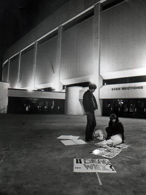 Mike Niehaus, 17, left, and Sally Rigby, 17, friends of three people killed Dec. 3, 1979, at the coliseum, sort their makeshift signs of protest before joining about 30 Finneytown friends in a candlelight a day later. One marcher's sign read: "What could replace 11 lives?"