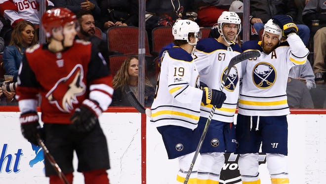 Buffalo Sabres left wing Benoit Pouliot (67) celebrates his goal against the Arizona Coyotes with defenseman Jake McCabe (19) and center Ryan O'Reilly, right, as Coyotes center Clayton Keller, left, skates away during the second period of an NHL hockey game Thursday, Nov. 2, 2017, in Glendale, Ariz. (AP Photo/Ross D. Franklin)