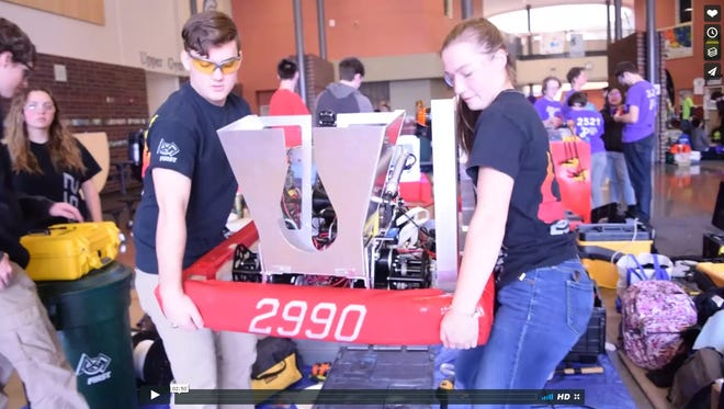 Hotwire Robotics team members carry the team's creation, Chaser, in preparation of FIRST Robotics competitions held in Houston.