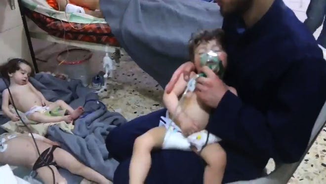 An image grab taken from a video released by the Syrian civil defense in Douma shows an unidentified volunteer holding an oxygen mask over a child's face at a hospital following a reported chemical attack on the rebel-held town on April 8, 2018.