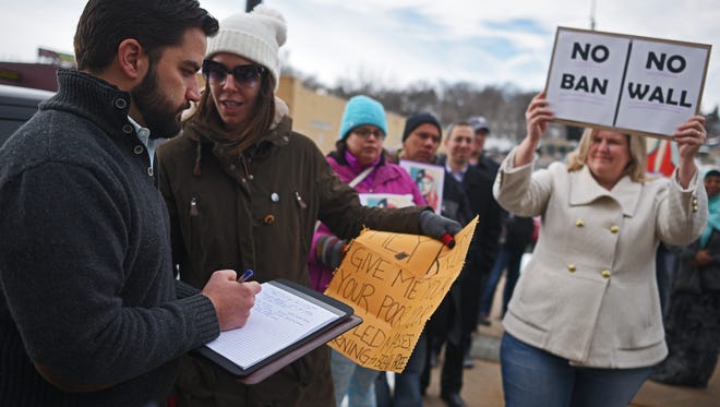 Andrew Curley, former Southeast Area Director for Rep. Kristi Noem's office, speaks with Kelly Sullivan as she takes part in a protest against President Donald Trump's executive order suspending the U.S. refugee program for 120 days and banning all immigrants from seven Muslim-majority countries for 90 days Tuesday, Jan. 31, 2017.