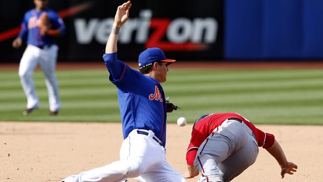 Mets second baseman Wilmer Flores, left, loses the ball while trying to tag Washington's Danny Espinosa during the ninth inning at Citi Field, on Sunday.