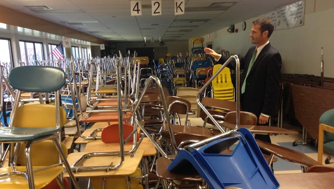 Algonac Schools superintendent John Strycker shows a roomful of desks and chairs for sale at a community garage sale event on Saturday.