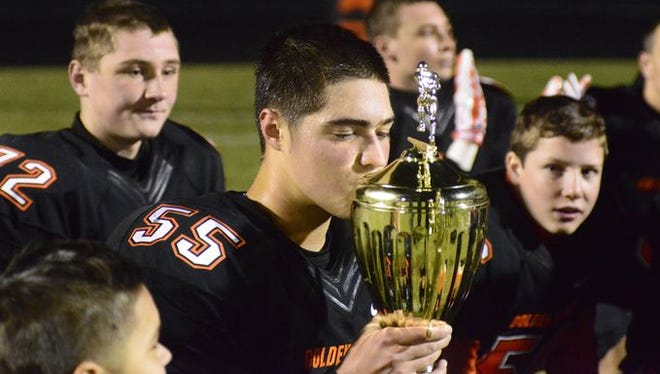 Gibsonburg's Joey Atkins kisses the Toledo Area Athletic Conference championship trophy after the Golden Bears' 48-18 win over Hilltop.