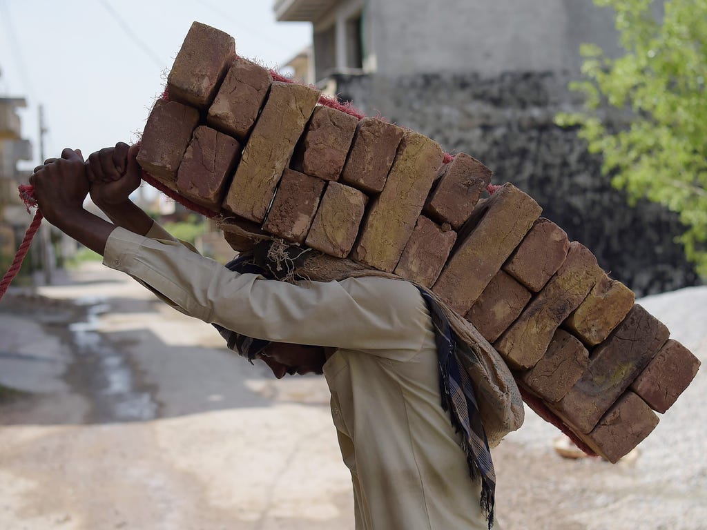 A Pakistani laborer carries bricks on his back at a construction site at a residential area in Islamabad.