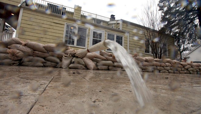 Water flows out of a sump pump pipe outside Fiddleheads Coffee Roasters, in Thiensville before a row of sandbags in place to heed the flood waters on Thursday, April 11, 2013.  The coffee shop at 192 Main St.  has sandbagged their backdoor against a rising Milwaukee River.  After three days of rain, rivers throughout southeastern Wisconsin were filled to the top of their banks and there were scattered reports of minor flooding in Sheboygan, Ozaukee, Milwaukee, Kenosha and a few inland counties. Photo by Mike De Sisti / MDESISTI@JOURNALSENTINEL.COM