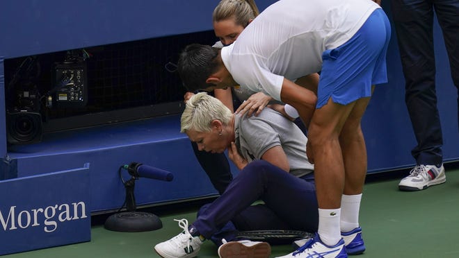 Novak Djokovic checks in with a line judge after he accidentally hit her in the neck with a tennis ball Sunday.