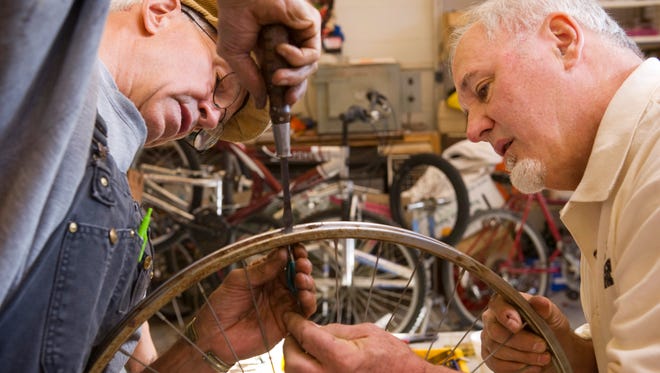 John Leavitt, left, and Pete Emery replace a spoke on a bicycle rim at Patchwork Central's bike shop.