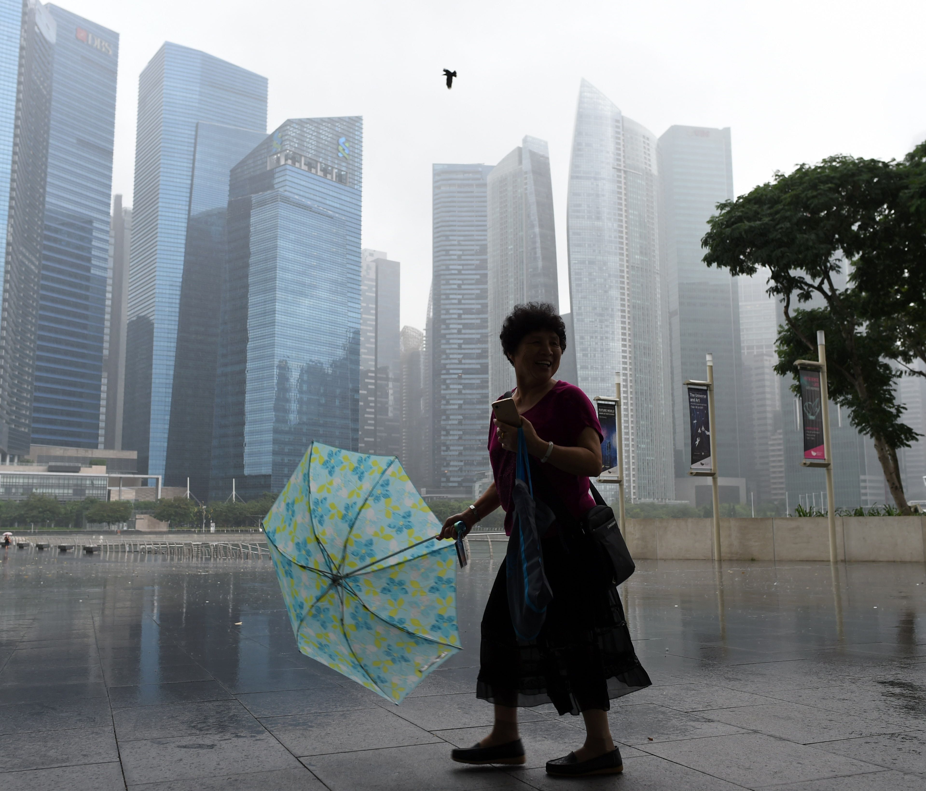 A woman with an umbrella walks away from the rain in Singapore on March 30, 2017.