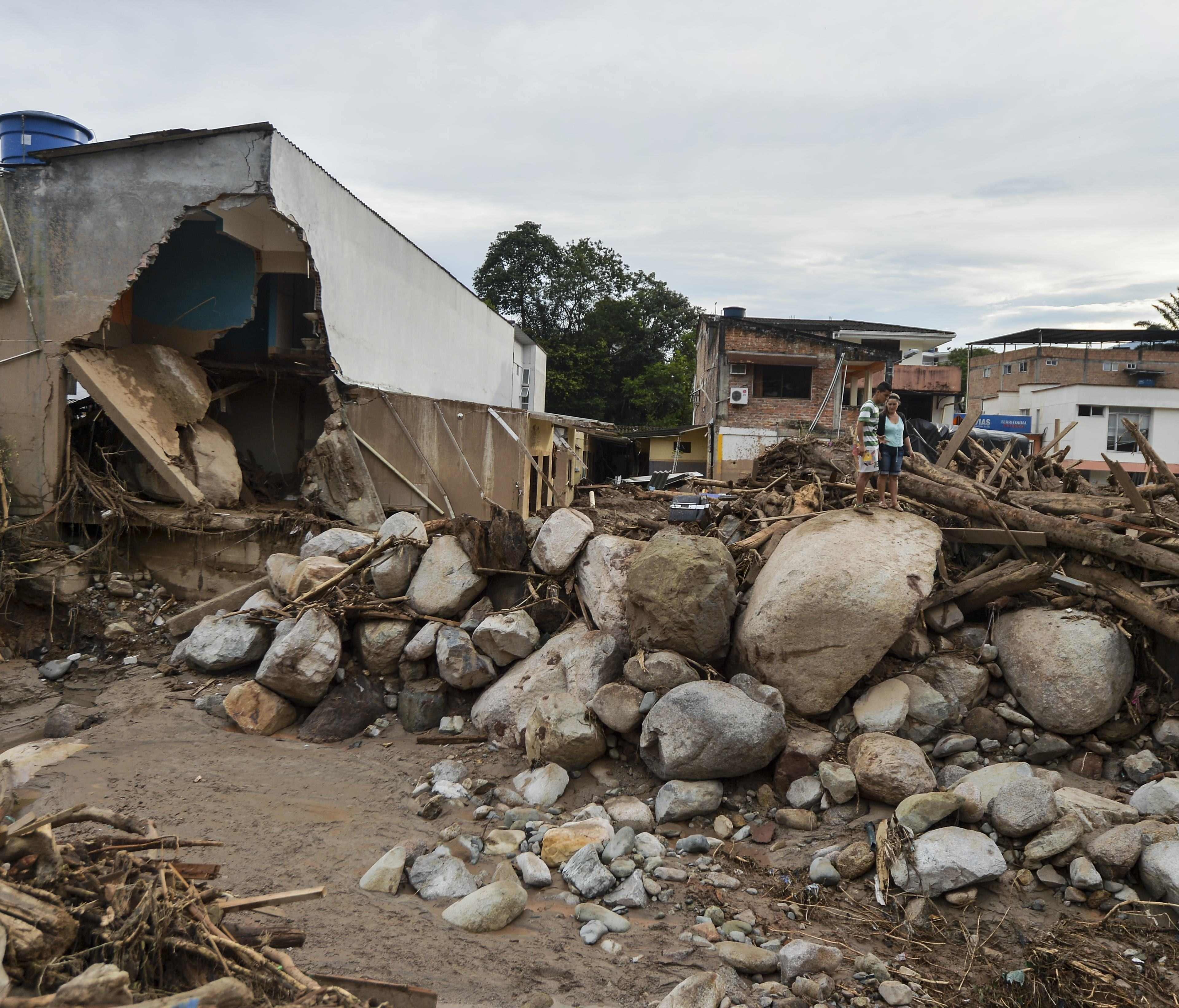 People look at damage caused by slides following heavy rains in Mocoa, Putumayo department, southern Colombia on April 2, 2017.   The death toll from a devastating landslide in the Colombian town of Mocoa stood at around 200 on Sunday as rescuers claw