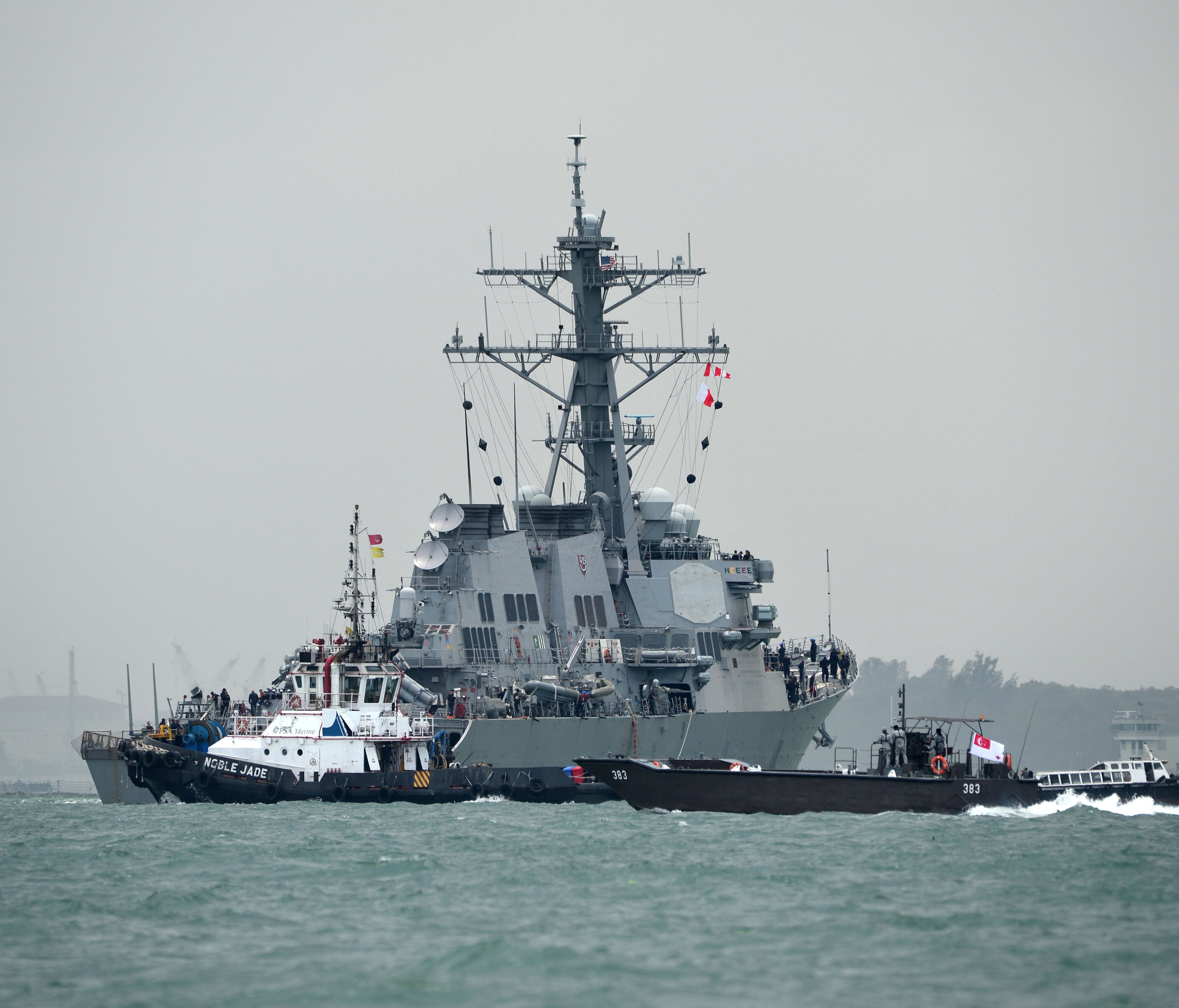 The guided-missile destroyer USS John S. McCain is guided by a tugboat after a collision with an oil tanker, outside Changi naval base in Singapore on Aug. 21, 2017.