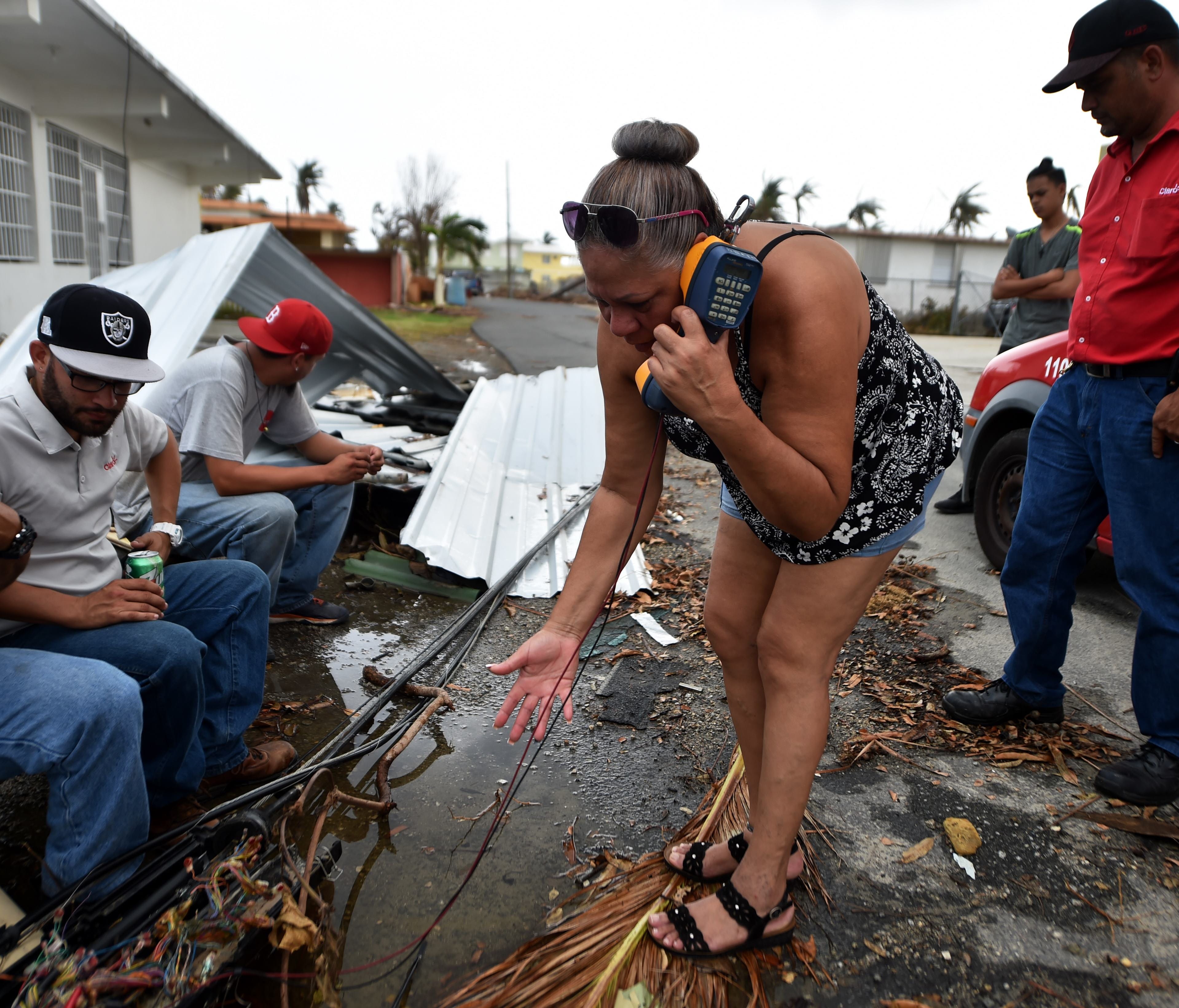 A woman tries to talk with her family to say that she is good condition while telephone technicians try to repaire the lines in Punta Santiago, Humacao, in the east of Puerto Rico, on September 27, 2017, one week after the passage of Hurricane Maria.