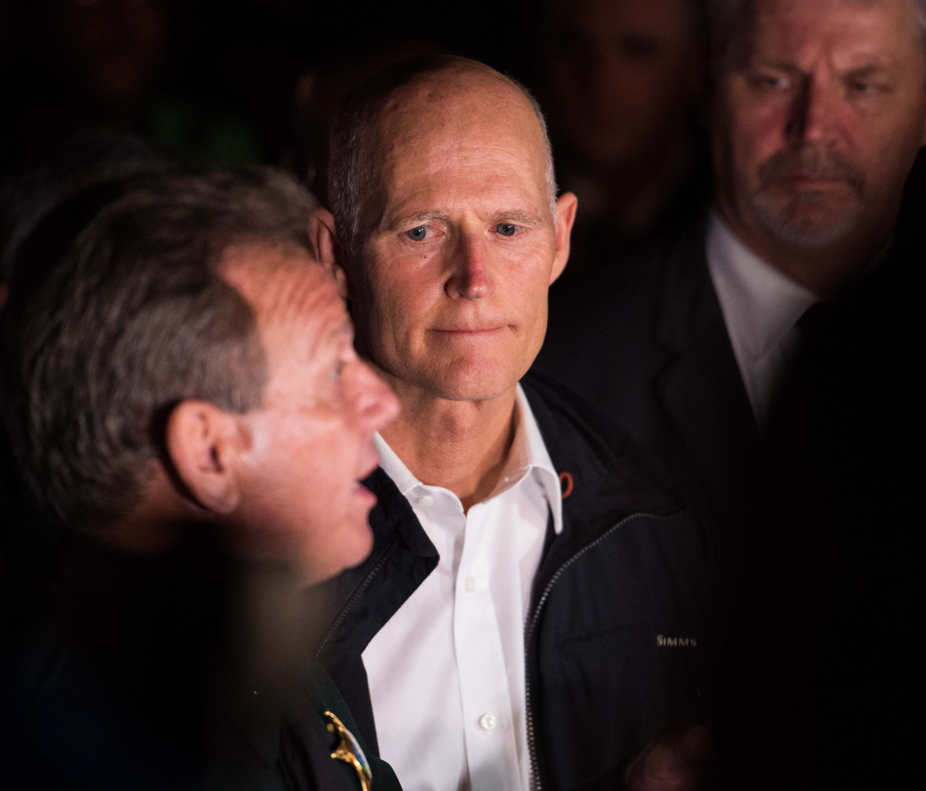 Florida Gov. Rick Scott listens to Broward County Sheriff Scott Israel speak at a news conference near Marjory Stoneman Douglas High School in Parkland on Wednesday, Feb. 14, 2018, following a mass shooting at the school.