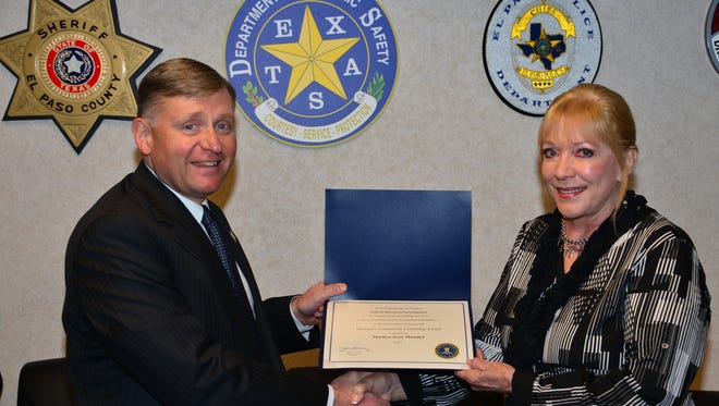 FBI Special Agent in Charge Douglas E. Lindquist presents a community leadership award to Marilyn Munden of El Paso on Tuesday.