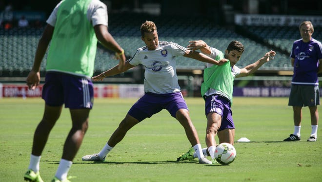 Orlando City SC players Tommy Redding, from left, and Rafael Ramos battle for a ball during a practice at Louisville Slugger Field on Monday as head coach Adrian Heath looks on. Aug. 25, 2015