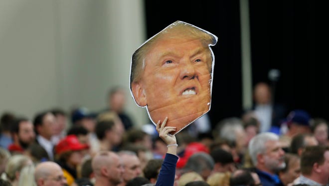A Donald Trump supporter held up a cut out of the Republican presidential front-runner's face during a rally in Louisville. Sen. John McCain, R-Ariz., is under increasing pressure to disavow Trump in his own Senate re-election race.