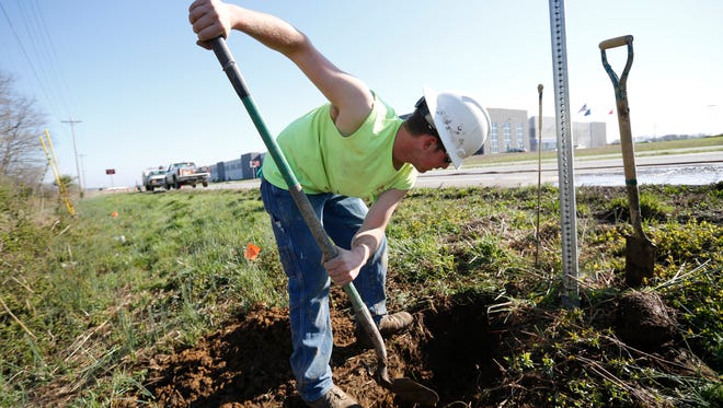 Addison Dorris uses a shovel to search for buried phone lines along Ind. 62 in Clark County. Dorris, who works for Dan Cristiani Excavating, and others were preparing for the extension of River Ridge Parkway.