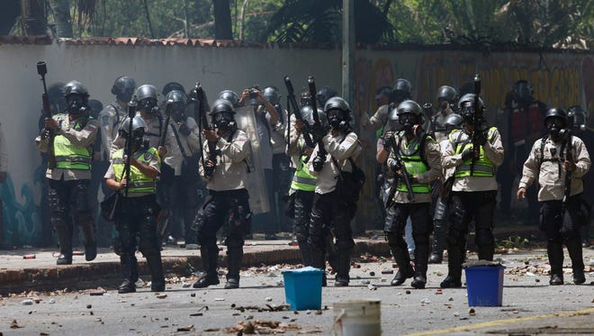 National Police stand ready to launch tear gas at student protesters outside the Central University of Venezuela in Caracas, Thursday, May 4, 2017. Students held demonstrations across Caracas Thursday as a two-month-old protest movement that shows no signs of letting up claimed more lives. (AP Photo/Fernando Llano)