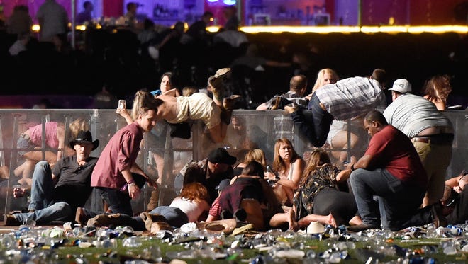 People scramble for shelter at the Route 91 Harvest country music festival after apparent gunfire was heard on Oct. 1 in Las Vegas. A gunman opened fire on a music festival in Las Vegas, leaving at least 59 people dead and 527 injured.