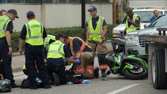 Lee County EMS work on a man who had been pinned under a car when his motorcycle was involved in a car on Fowler Street on Tuesday. The man suffered a non-life-threatening ankle injury.