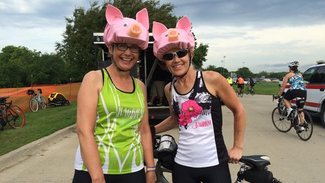 Gloria Mesick, 53, (left) and Jackie Rouse, 53, of Bettendorf, prepare for the BACoon Ride by donning some pig headgear at Centennial Park in Waukee Saturday morning.