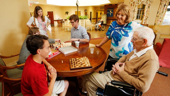 Trish Gaylord visits with her father, Bill Nangle, 89, as he plays a game of chess with Ryan Howard Wednesday, May 11, 2016 at Creasy Springs Health Campus, 1750 S. Creasy Lane in Lafayette. Howard and other students from McCutcheon High School have been visiting Creasy Springs regularly to play chess with Nangle. In the background are McCutcheon students Joshua Stalbaum, from left, Alex Storz and Nathan Chapman.