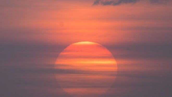 A pastel sunrise through clouds on the horizon off Midtown Beach in Palm Beach.