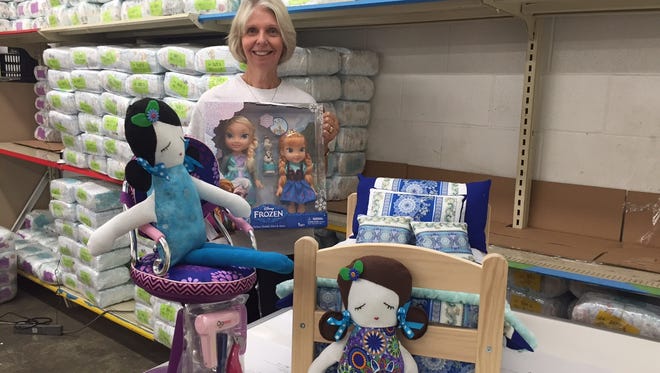 Jill Bright, executive director for Diaper Bank of the Ozarks, poses with some of the door prizes that will be given away at the Dolly and Me Tea Party Nov. 7.