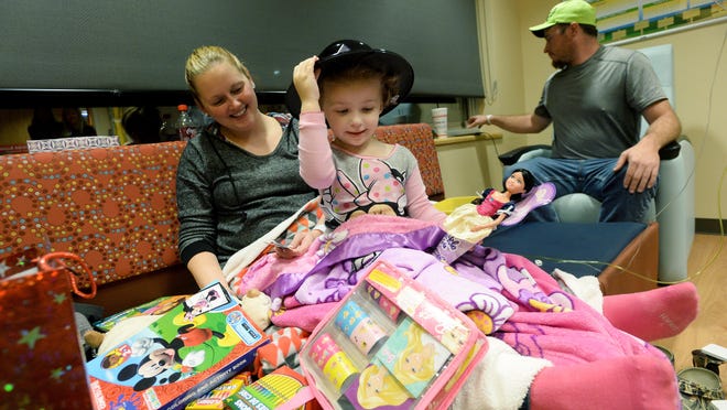 Ellie Moody, 2, adjusts her new hat as she surveys the toys given to her by troopers from the North Carolina Highway Patrol while sitting with her parents, Krystal and T.J., in her room at Mission Hospital in 2015.