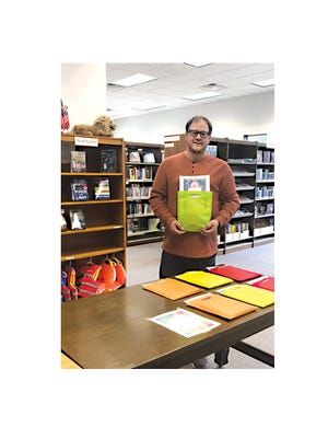 Andy Kelton, Library Director, is holding one of the weekly take home kits for the Summer Reading program.