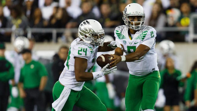 Oregon quarterback Marcus Mariota (8) hands off to running back Thomas Tyner (24) during the second quarter of an NCAA college football game against South Dakota in Eugene, Ore., Saturday, Aug. 30, 2014. (AP Photo/Ryan Kang)