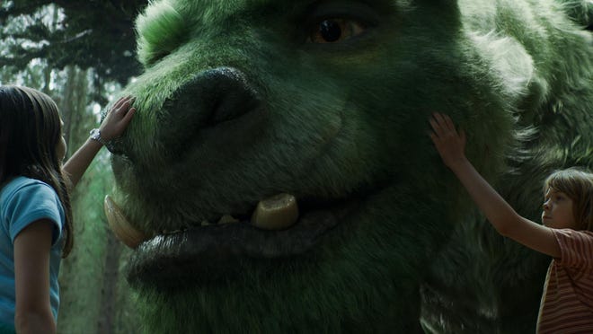 Oona Laurence as Natalie, left, and Oakes Fegley as Pete, appear with Elliot the dragon in a scene from “Pete’s Dragon.”