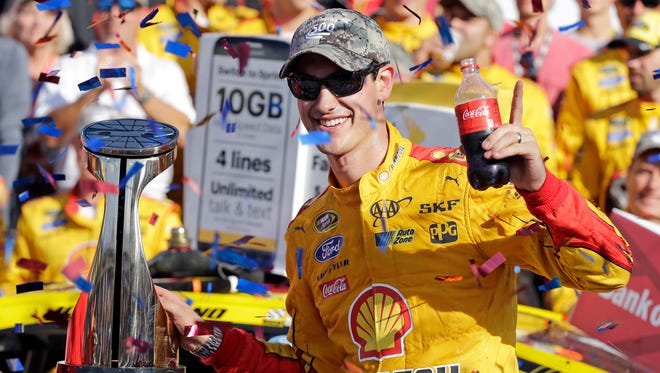 Joey Logano poses with the trophy in Victory Lane after winning the NASCAR Sprint Cup series auto race at Charlotte Motor Speedway in Concord, N.C., Sunday, Oct. 11, 2015. (AP Photo/Terry Renna)